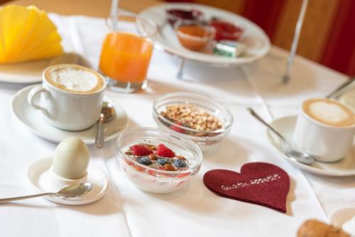 a table topped with cups of coffee and breakfast foods at Eich-hof in Caldaro