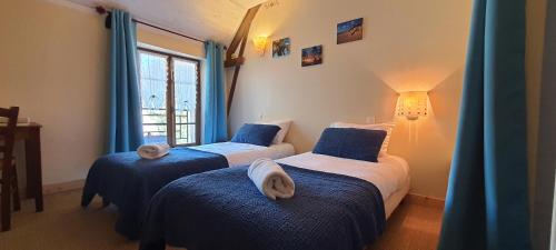 two beds in a room with blue curtains at Le Castellou in Conques