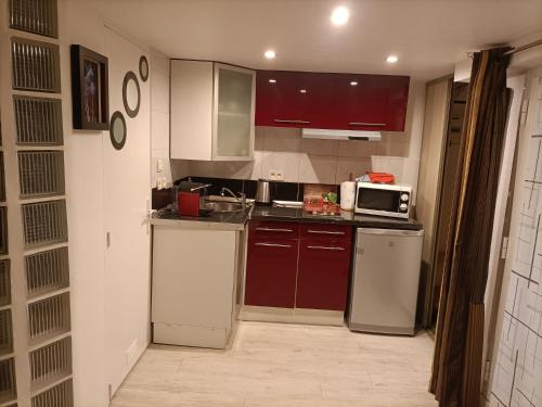 cocina con armarios rojos y blancos y microondas en Cielito Lindo, en Montpellier