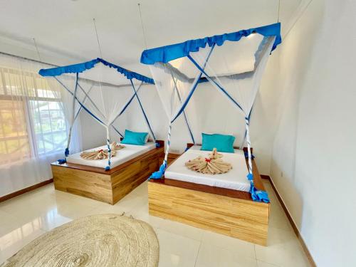 2 letti in una camera con tende blu di TIANDE Boutique Hotel a Pwani Mchangani