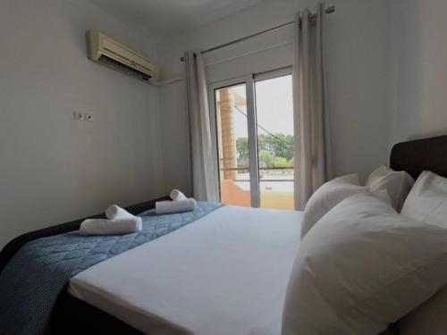 a bedroom with two beds and a large window at Bouvegio Apartments Vera in Afantou