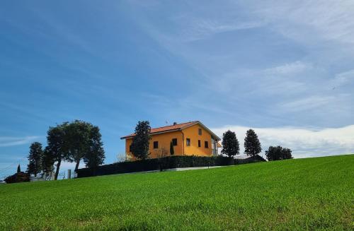żółty dom na szczycie zielonego wzgórza w obiekcie Casale Ermo Colle w mieście San Filippo
