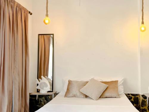 a bedroom with a white bed and a mirror at Samarian Hostel in Taganga