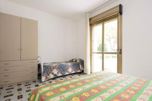 a bedroom with a bed and a dresser and a window at Apartment in Lignano 21638 in Lignano Sabbiadoro