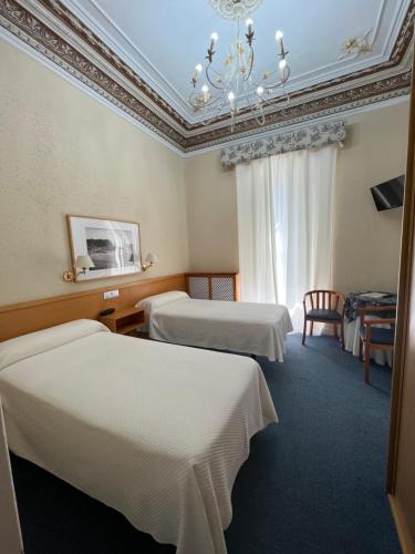 Habitación de hotel con 2 camas y lámpara de araña. en Hotel Ramona, en Laredo
