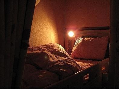 1 dormitorio con 1 cama con luz en la pared en Guesthouse Nara Backpackers, en Nara