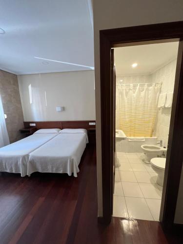 1 dormitorio con 1 cama grande y baño en Hotel Ramona, en Laredo