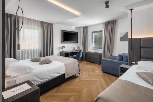 una camera d'albergo con 2 letti e una scrivania di Hotel Cittar a Novigrad Istria