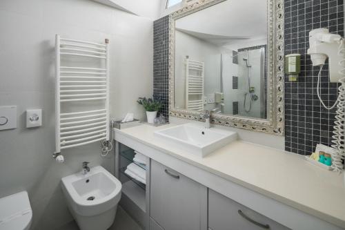a bathroom with a sink and a toilet and a mirror at Hotel Cittar in Novigrad Istria