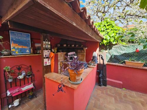 un bâtiment rouge avec un comptoir recouvert de plantes en pot dans l'établissement Les violettes, à Menton