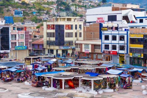 a group of tables and umbrellas in a city at HOTEL El INDIO in Otavalo