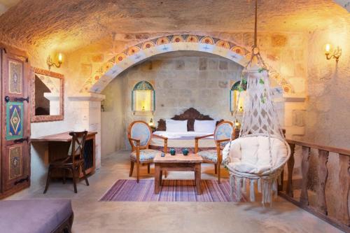 a living room with a table and a stone wall at Capp Royal Cave HOTEL in Ürgüp