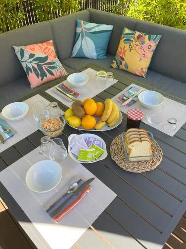 einen Tisch mit Teller mit Lebensmitteln und Obst darauf in der Unterkunft Chambres dans maison familiale in Le Mans