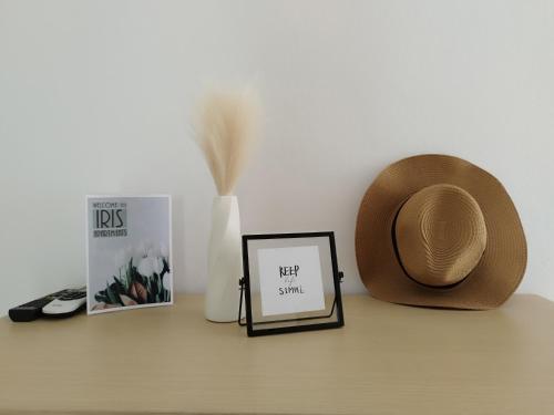 a hat and a picture on a table next to a book at Iris Apartments Ksamil in Ksamil