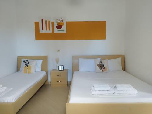 two beds in a room with white sheets at Iris Apartments Ksamil in Ksamil