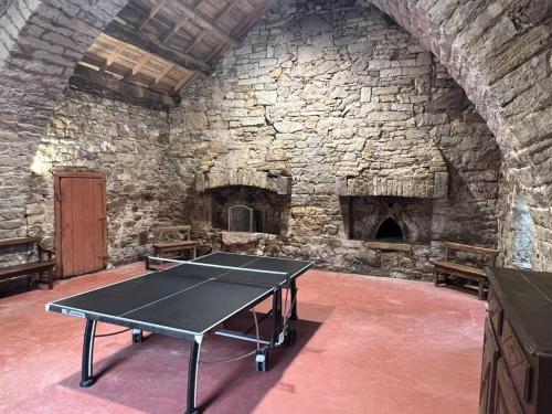 - une table de ping-pong dans une pièce dotée d'un mur en pierre dans l'établissement Les Distinguées -Aux Bories de Prévinquières, à Recoules-Prévinquières