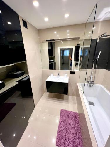 łazienka z umywalką, wanną i fioletowym dywanem w obiekcie Spanko w centrum w Zielonej Górze