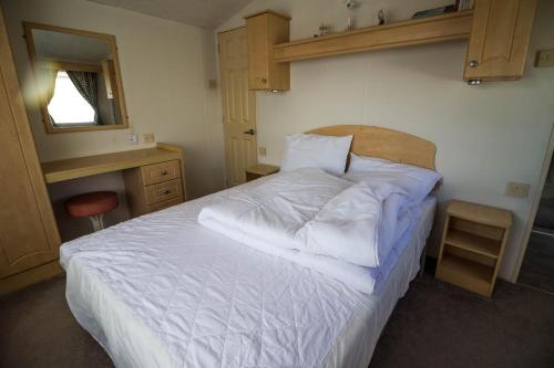 a bedroom with a white bed and a mirror at 6 Berth Caravan For Hire In Hunstanton At Manor Park Holiday Park Ref 23004a in Hunstanton