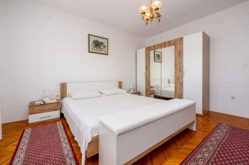 a bedroom with a large white bed and a mirror at Apartment in Crikvenica 5224 in Dramalj