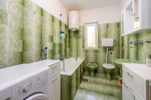 a green and white bathroom with a sink and a toilet at Apartment in Crikvenica 5224 in Dramalj