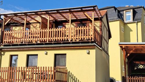 a large yellow house with a wooden deck at Pension am Elberadweg in Radebeul
