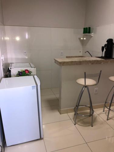 una cucina con frigorifero e bancone con sgabelli di Flat Hotel a Guanambi