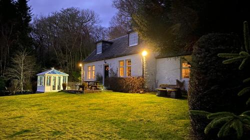 une maison blanche avec un kiosque dans une cour la nuit dans l'établissement Dubh Loch Cottage, à Rowardennan