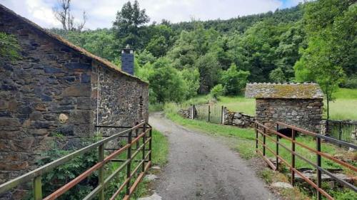 uma estrada de terra ao lado de um edifício de pedra e uma cerca em VUT El Refugio em Villablino