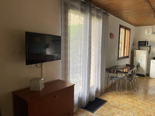 a living room with a television and a table and a window at Vénosc-Les 2 Alpes , Rez de jardin in Vénosc