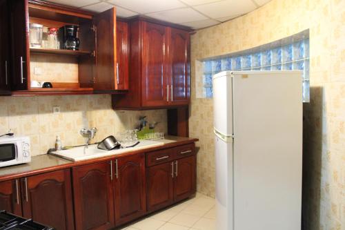 a kitchen with a white refrigerator and wooden cabinets at Residence Le Carat in Douala