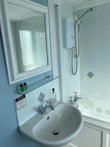 een witte badkamer met een wastafel en een douche bij Honeypot Guest House in Crail