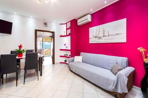 a living room with a couch and a pink wall at Apartment in Crikvenica 27606 in Crikvenica