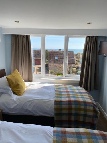 a bedroom with a bed and a large window at Honeypot Guest House in Crail
