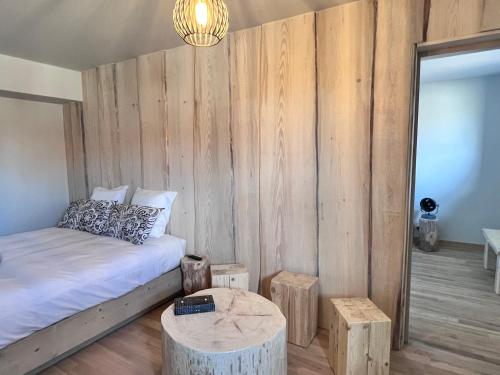 a bedroom with a bed with a wooden wall at Hôtel En Tilleul in Pont-du-Navoy