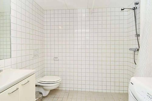 ein weiß gefliestes Bad mit einem WC und einer Dusche in der Unterkunft 4-Bedroom-Apt for 7/Oslo Central in Oslo