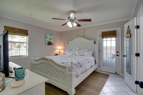 a bedroom with a white bed and a ceiling fan at Charming Family Cottage Near Pass Christian Beach! in Pass Christian