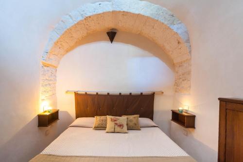 a bedroom with an arch above a bed with two lamps at La corte di Ercole in Alberobello