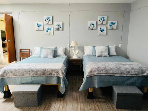 a bedroom with two beds and a table and pictures on the wall at Residencia Ibarra in Santa Cruz de la Soledad