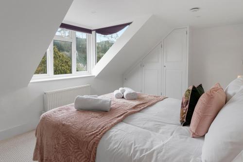 a white bedroom with a bed with two towels on it at 9 Riverside in Sidmouth