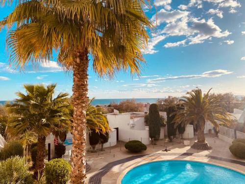 une villa avec un palmier et une piscine dans l'établissement LE CALI, P2 Cabine dans une résidence avec piscine, vue mer et parking privé, à La Grande Motte