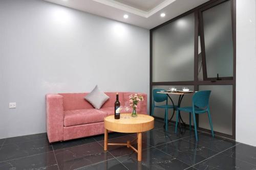 uma sala de estar com um sofá rosa e uma mesa em Căn hộ studio full nội thất tại Tây Hồ em Hanói