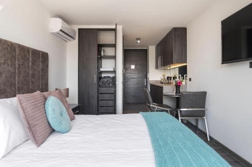 1 Schlafzimmer mit einem weißen Bett und einer Küche in der Unterkunft Hermoso Apartamento en el Casco Histórico de Santiago in Santiago