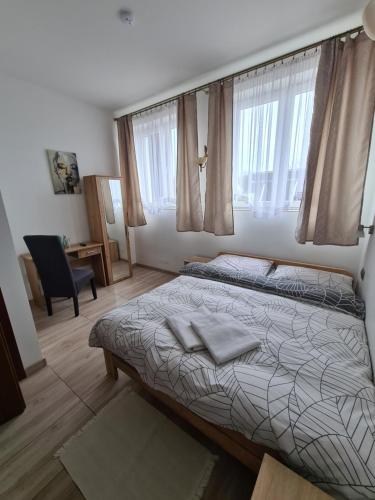 a bedroom with a bed and a chair and windows at Motel i Restauracja "Pod Basztą" in Nagłowice