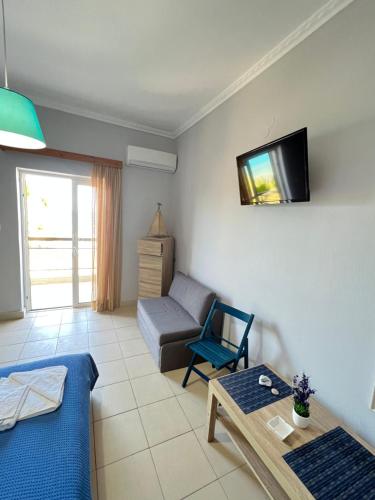 Una sala de estar con un sofá y un televisor en la pared. en Nefeli Rooms, en Agia Marina de Nea Kydonia