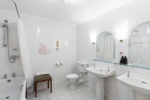 a white bathroom with a toilet and a sink at Cally Palace Hotel & Golf Course in Gatehouse of Fleet