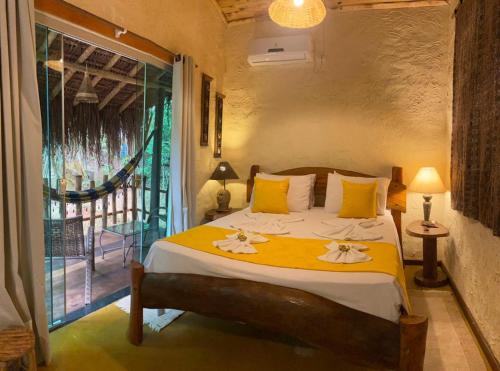 Un dormitorio con una cama con almohadas amarillas y una ventana en Pousada Do Lado de Lá, en Pirenópolis