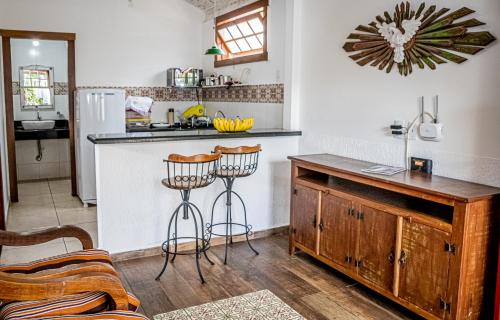 a kitchen with a counter and two stools at Flats Casa de Violeta in Tiradentes
