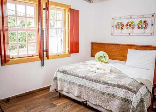 a bedroom with a bed and two windows at Flats Casa de Violeta in Tiradentes