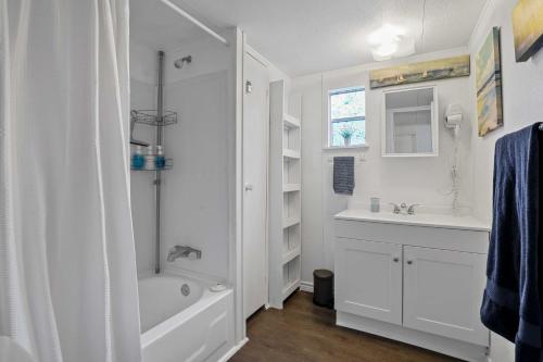 La salle de bains blanche est pourvue d'une baignoire et d'un lavabo. dans l'établissement Charming Lake Dallas Home with Furnished Patio!, à Lake Dallas