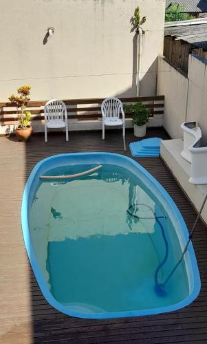 a pool on the roof of a building with two chairs at Por do Sol in Florianópolis